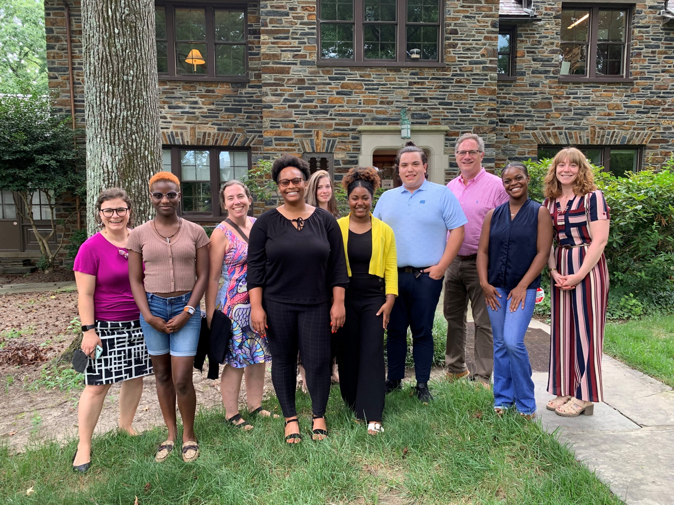 Photo of a small group of student interns and communications professionals smiling on Duke University's campus